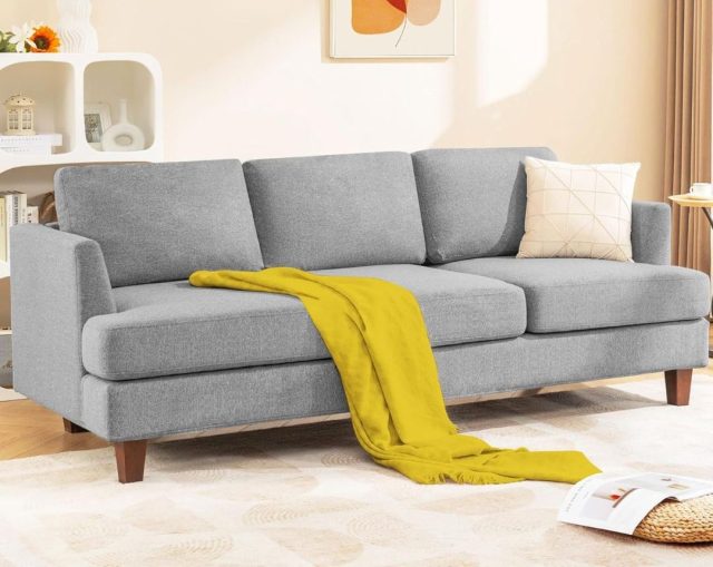 grey three seat sofa with a yellow throw draped across the cushions