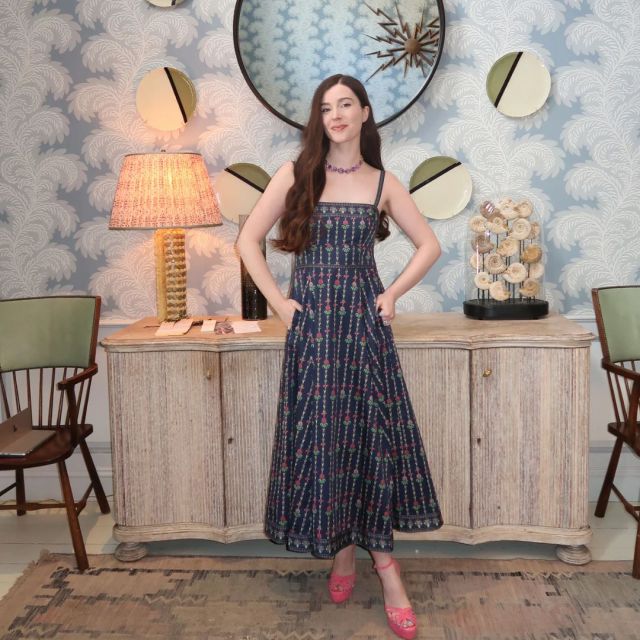 woman standing in classic dining room wearing navy floral sleeveless dress