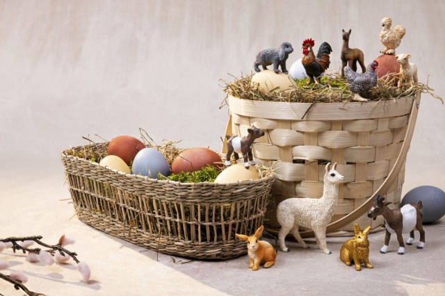 A lifestyle shot of baskets filled with eggs and Schleich farm animals, which are one of the best non-candy easter basket ideas