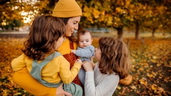 A mom and her three kids out in the park in autumn enjoying autumn family activities