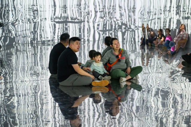 A family sitting in a mirrored room at Kidspace Museum's Wired for Wonder exhibit