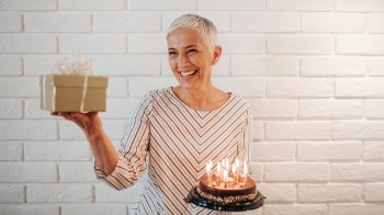 An older woman holding a gift and a cake to represent the latest baby trend, grandma showers