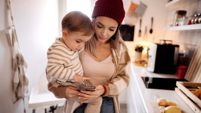 a mother holding her baby while looking at her phone, maybe watching the latest Irish DPC campaign