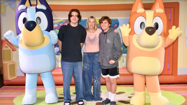A mom with her two older sons, posing with Bluey and Bingo, testing the waters on a disney cruise for teens