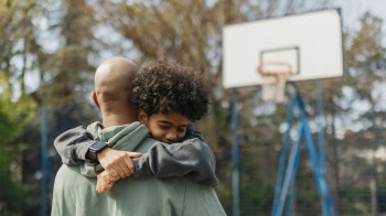 a dad and his son playing basketball and hugging for a story on things we should all be telling our sons