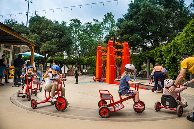 Kids playing on big tricycles at Kidspace Campout